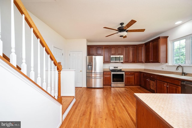 9129 Pebble Beach Ln, King George, VA 22485 - kitchen with stainless steel appliances, a sink, light countertops, light wood-style flooring, and ceiling fan