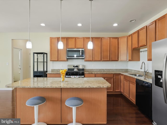 kitchen with a center island, a sink, dark wood-style flooring, light stone countertops, and appliances with stainless steel finishes
