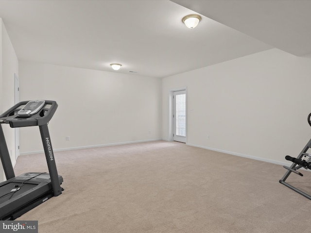 workout room featuring baseboards and light carpet