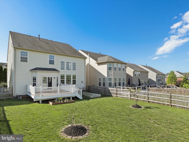 back of property with a lawn, a deck, a residential view, and a fenced backyard