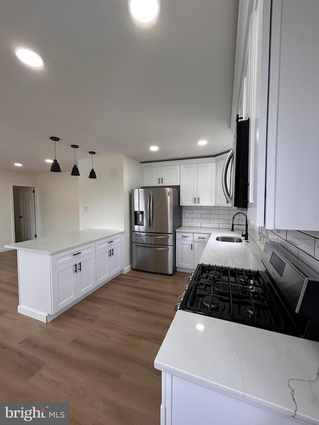 kitchen featuring recessed lighting, a sink, a peninsula, backsplash, and appliances with stainless steel finishes