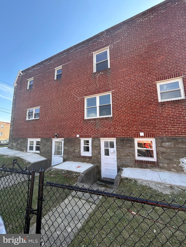 back of house with brick siding and fence