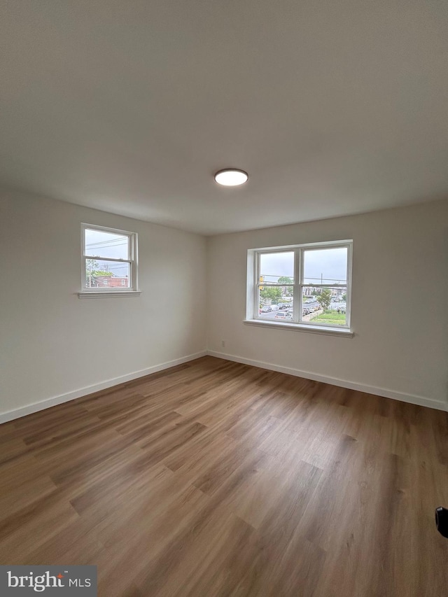 spare room featuring a wealth of natural light, wood finished floors, and baseboards