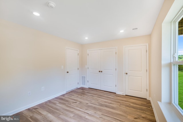 unfurnished bedroom featuring baseboards, multiple windows, recessed lighting, and light wood-style flooring