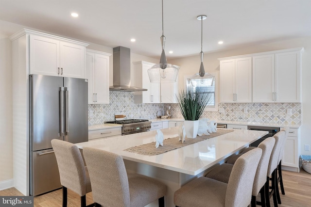 135 Walnut Ave, North Wildwood, NJ 08260 - kitchen with wall chimney range hood, white cabinetry, high end appliances, a kitchen bar, and a kitchen island