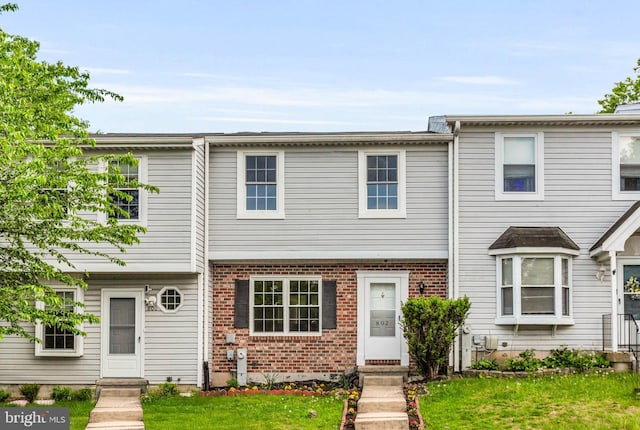 townhome / multi-family property with brick siding and a front yard