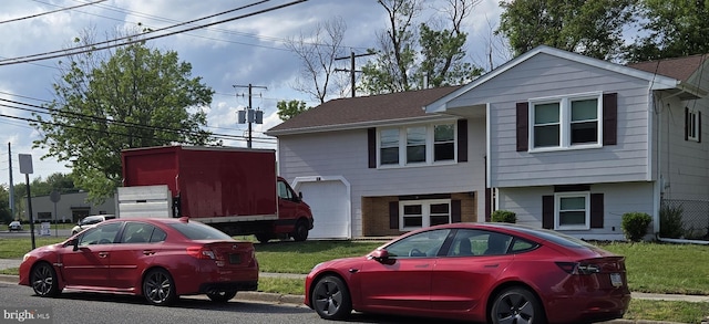 view of front of house with brick siding, a garage, and a front yard