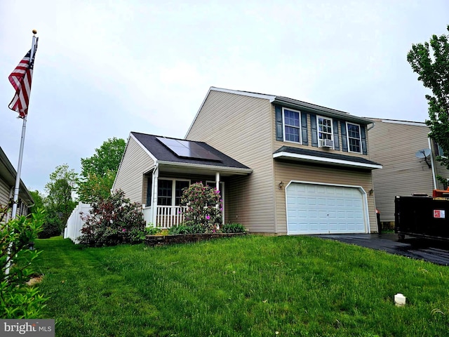 view of front of property featuring covered porch, an attached garage, driveway, roof mounted solar panels, and a front lawn