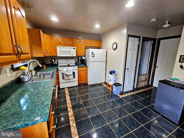 kitchen with dark countertops, brown cabinets, a sink, and white appliances