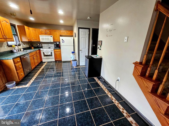 kitchen featuring recessed lighting, brown cabinetry, white appliances, a sink, and dark countertops