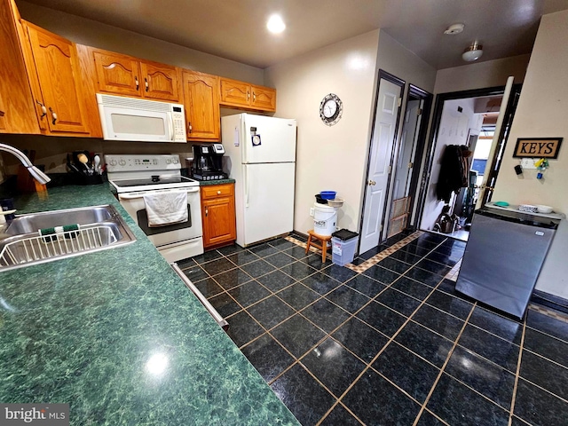 kitchen featuring a sink, white appliances, dark tile patterned flooring, and dark countertops