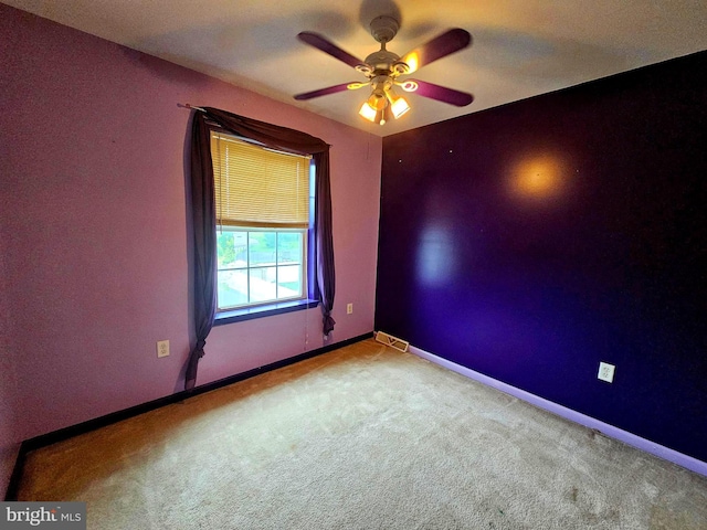 carpeted empty room with baseboards, visible vents, and ceiling fan
