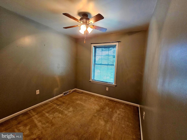 carpeted spare room featuring baseboards, a ceiling fan, and visible vents