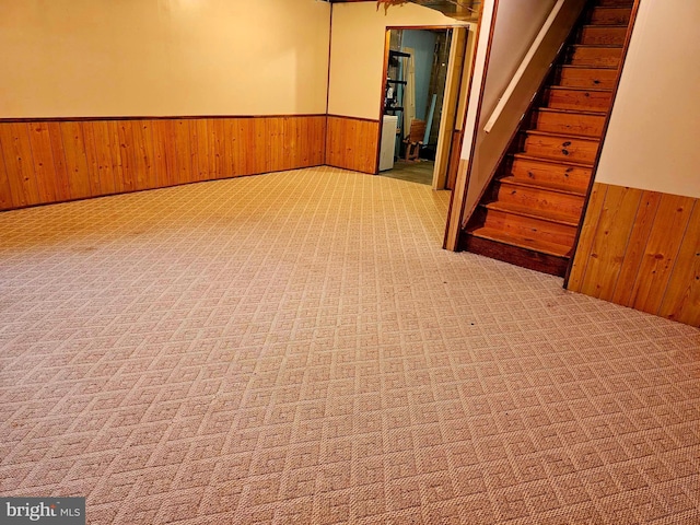 basement featuring a wainscoted wall, wood walls, carpet floors, and stairs