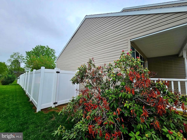 view of side of property featuring fence and a lawn