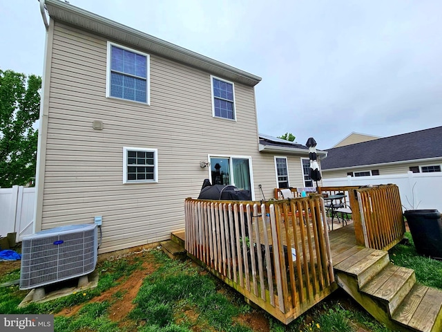 rear view of house featuring central AC unit, a wooden deck, and fence