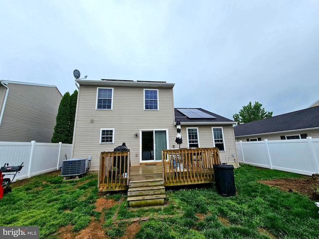rear view of property featuring a fenced backyard, solar panels, a yard, and central AC