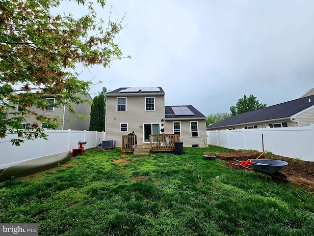 back of property with crawl space, a fenced backyard, a wooden deck, solar panels, and a lawn