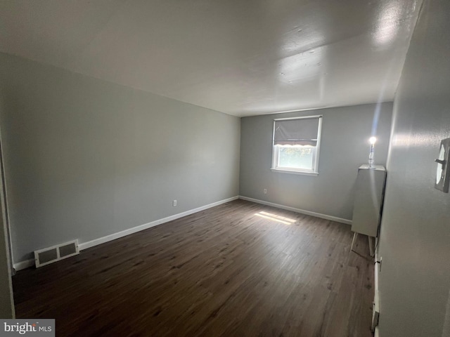 spare room with baseboards, dark wood finished floors, and visible vents