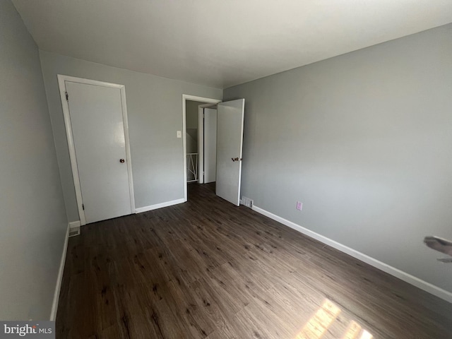 unfurnished bedroom featuring baseboards and dark wood-type flooring