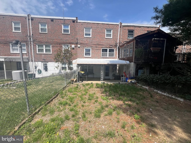 rear view of property featuring brick siding and fence