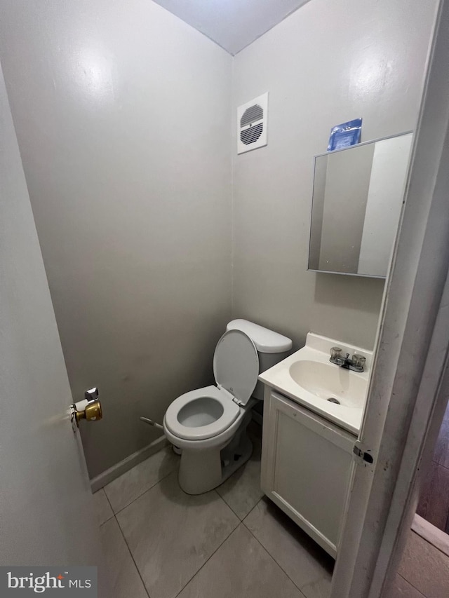 half bathroom featuring vanity, tile patterned flooring, and toilet