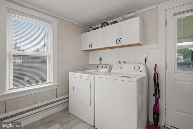 clothes washing area with tile walls, baseboard heating, ornamental molding, washer and clothes dryer, and cabinet space