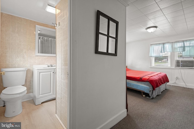 bedroom featuring baseboards, tile walls, and a sink