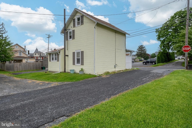view of side of property featuring fence and a lawn