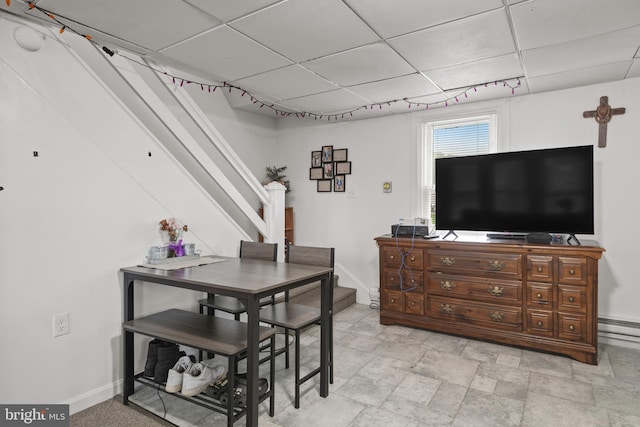 dining space featuring a baseboard radiator, stairs, baseboards, and a drop ceiling