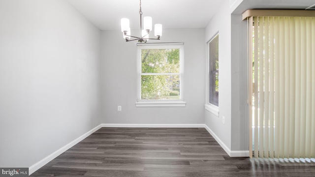 unfurnished dining area featuring baseboards, a notable chandelier, and dark wood-type flooring