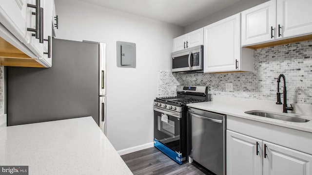 kitchen featuring dark wood-style floors, light countertops, tasteful backsplash, a sink, and appliances with stainless steel finishes