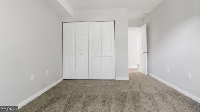 unfurnished bedroom featuring carpet floors, baseboards, and a closet