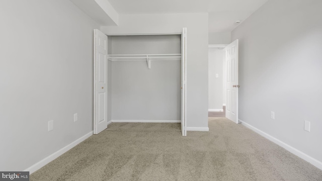 unfurnished bedroom featuring baseboards, carpet, and a closet