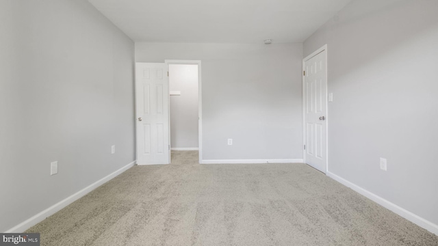 unfurnished bedroom featuring carpet flooring, baseboards, and a spacious closet