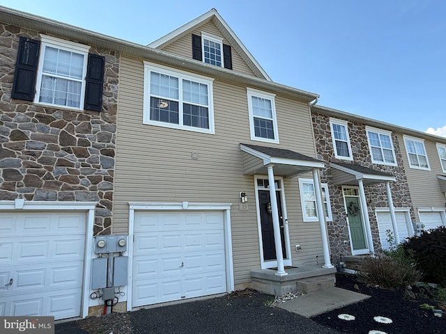 view of property featuring an attached garage and stone siding