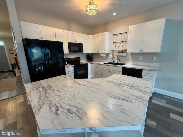 kitchen with white cabinets, dark wood-style flooring, a sink, and black appliances