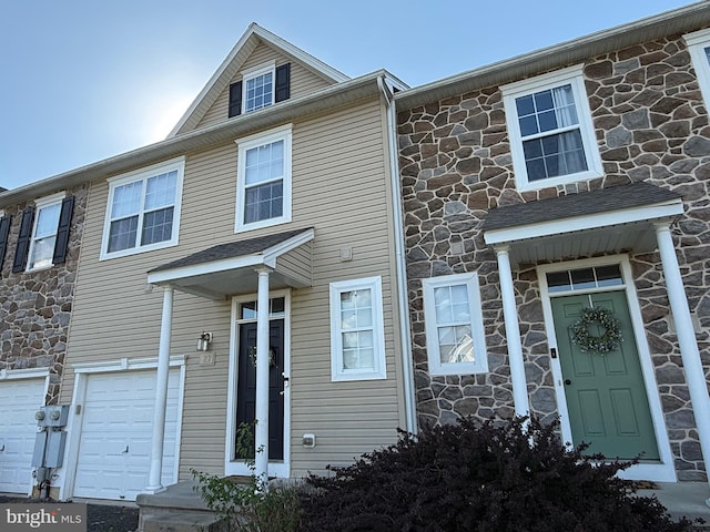 view of property featuring an attached garage and stone siding