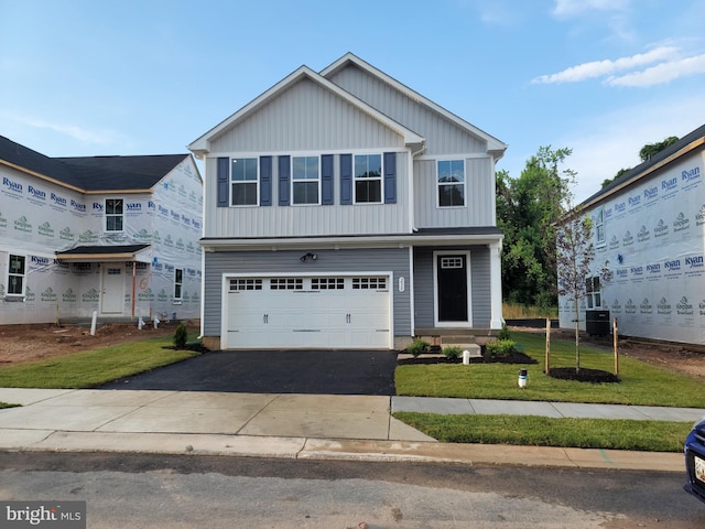 traditional-style home with board and batten siding, driveway, a front yard, and a garage