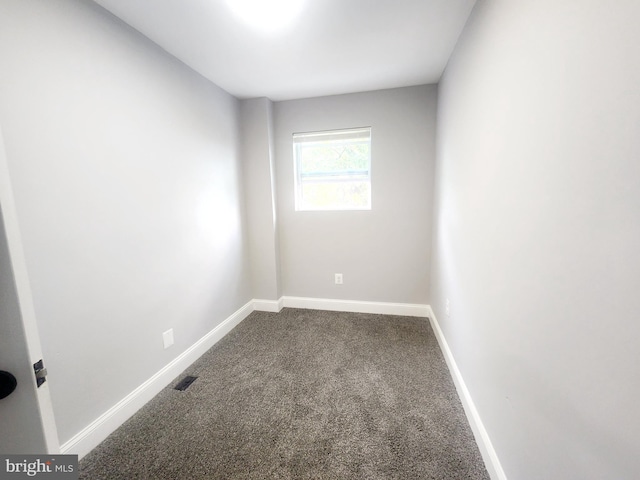 empty room with dark colored carpet, baseboards, and visible vents