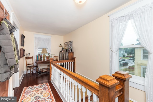 corridor with baseboards, wood finished floors, and a wealth of natural light