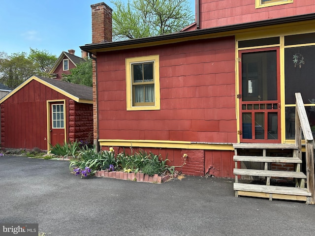 view of side of property featuring an outdoor structure, a chimney, and entry steps