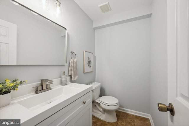 bathroom with toilet, vanity, and baseboards