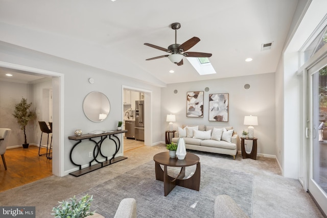 living area with ceiling fan, a skylight, lofted ceiling, light carpet, and recessed lighting