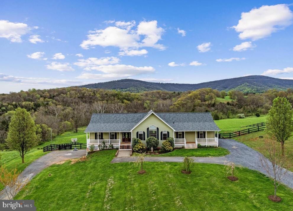 single story home with a porch, a mountain view, and a wooded view