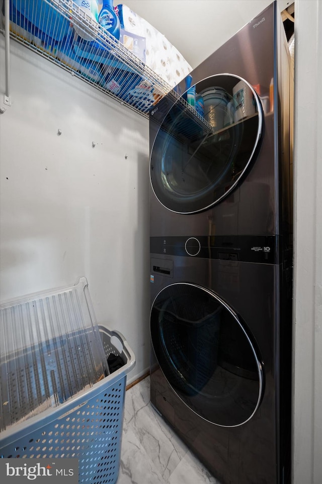 washroom with laundry area, stacked washer / dryer, and marble finish floor