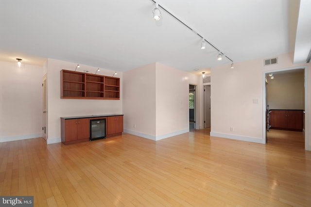 1301 N Ode St Unit 135, Arlington, VA 22209 - unfurnished living room with rail lighting, beverage cooler, light wood-type flooring, and baseboards