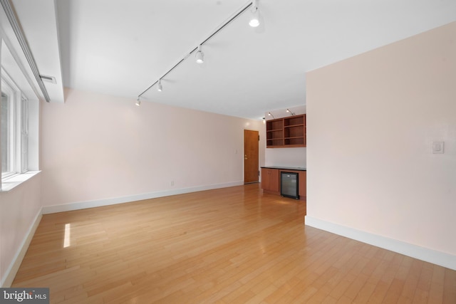 1301 N Ode St Unit 135, Arlington, VA 22209 - unfurnished room featuring track lighting, baseboards, light wood finished floors, and wine cooler