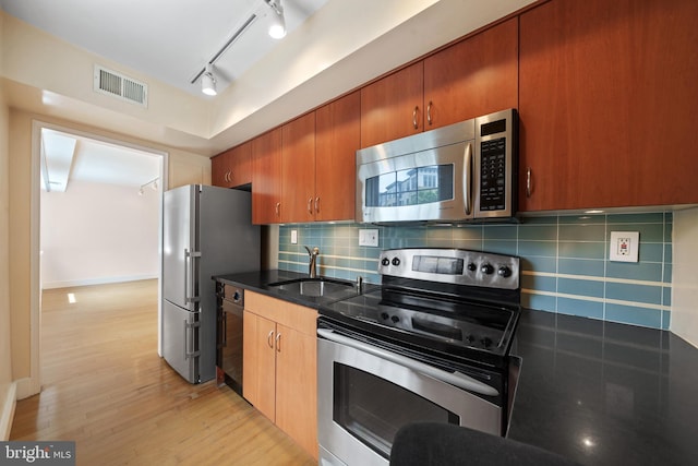 1301 N Ode St Unit 135, Arlington, VA 22209 - kitchen with stainless steel appliances, a sink, light wood finished floors, rail lighting, and backsplash