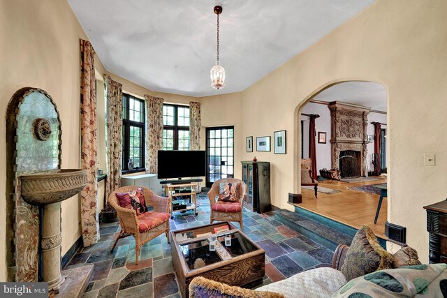 218 Parkside Ave, Trenton, NJ 08618 - living room with arched walkways, stone tile floors, a fireplace with raised hearth, and a chandelier